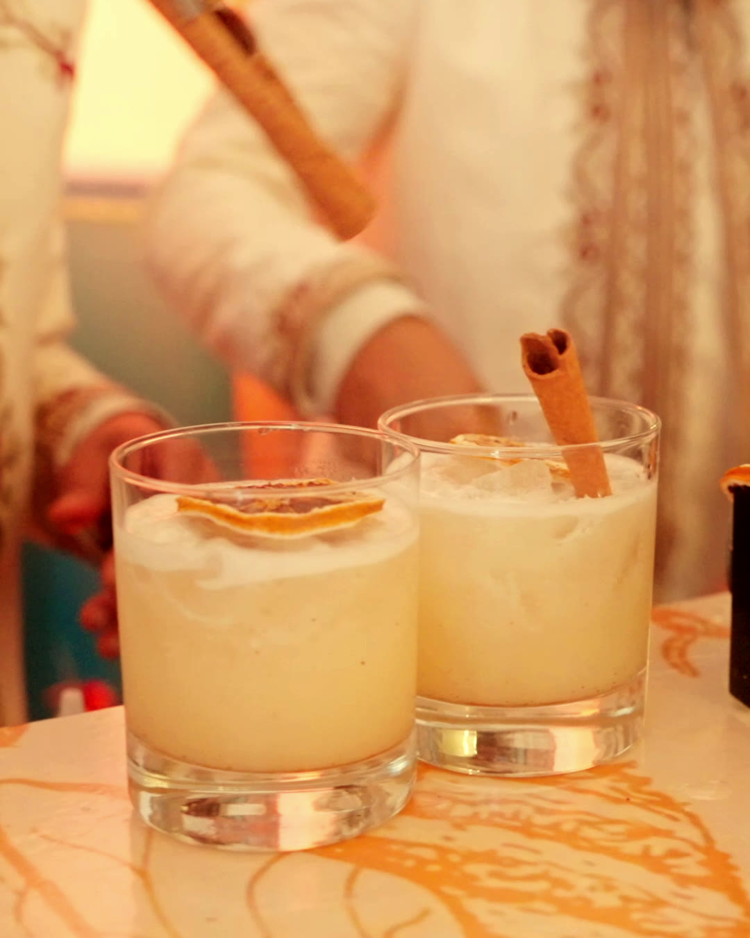 Bartender en tenue traditionnelle servant deux cocktails à la cannelle